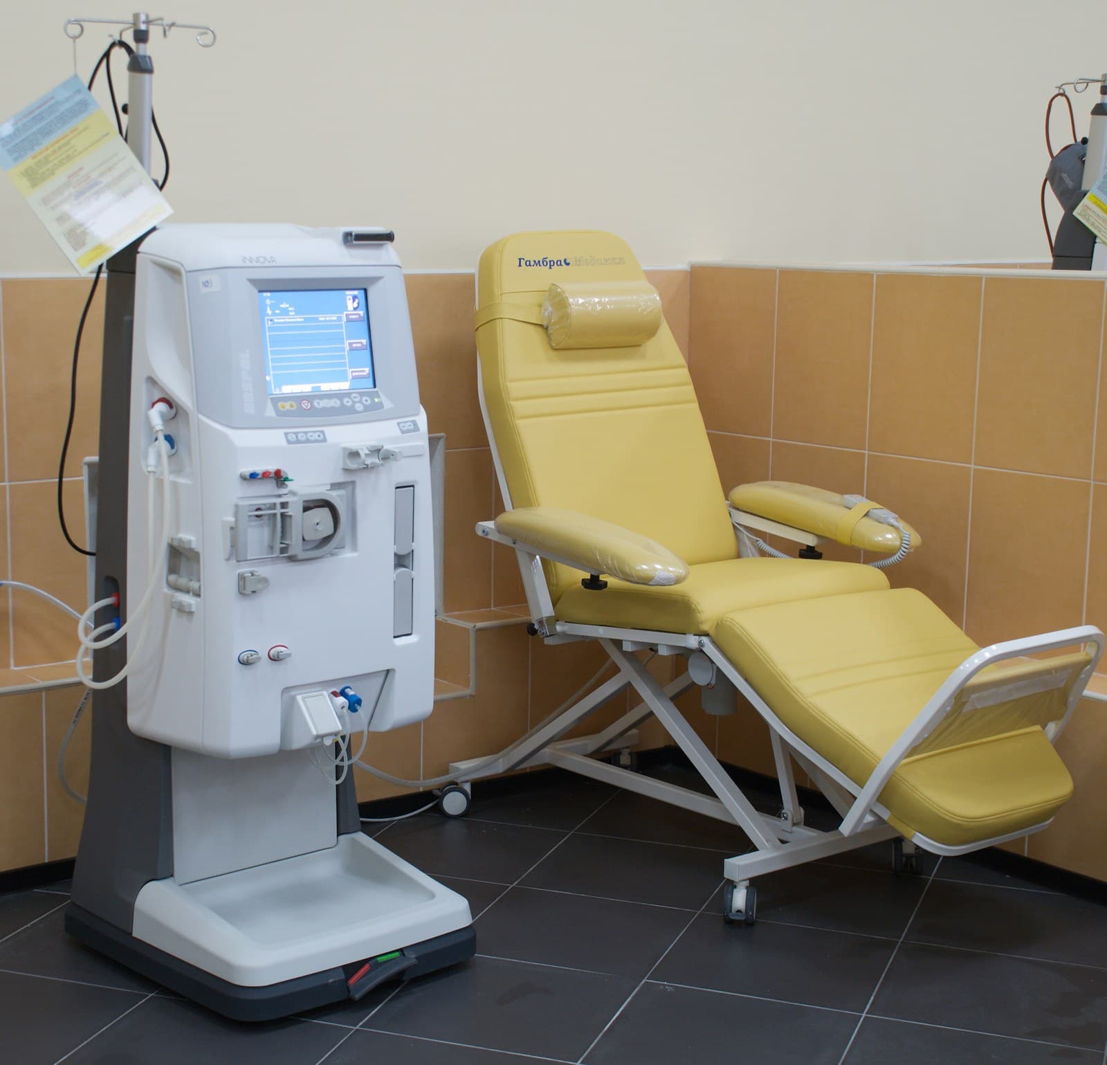 Máquina de hemodiálise ao lado de uma poltrona de tratamento, em sala hospitalar, sem pacientes.